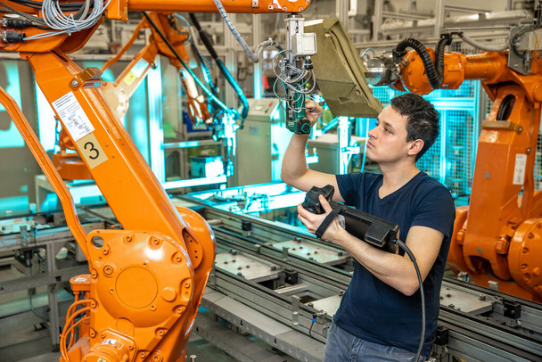 Bir üretim mühendisi tarafından yeni bir ürün için robot kollarının programlanması - Fotoğraf, Görsel