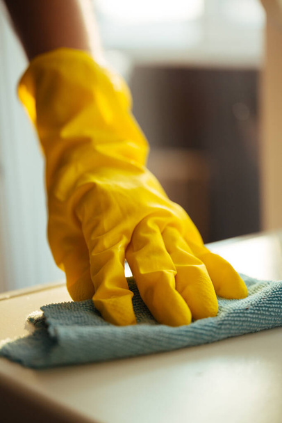 Cleaning the house during the quarantine. The girl washes the dirty and dusty floor with the yellow cloth protective gloves yellow - Фото, зображення