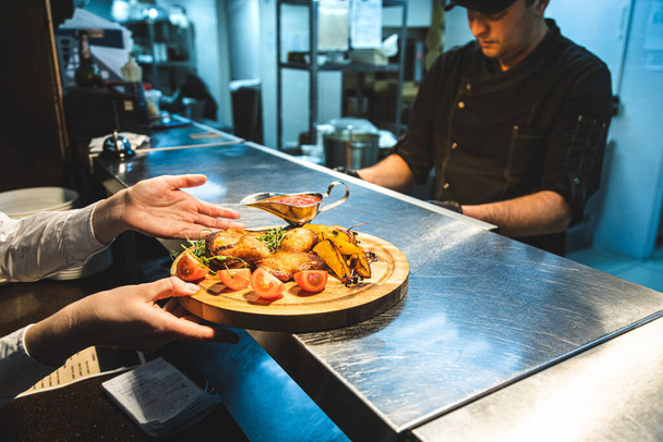 Los camareros recogen las comidas preparadas en un restaurante en el mostrador para dispensar platos
 - Foto, Imagen
