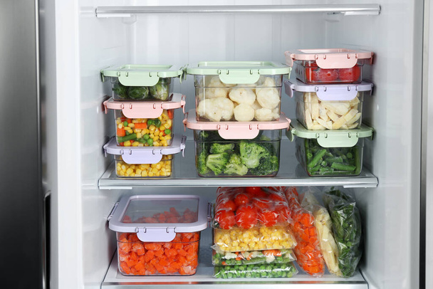 Plastic bags and containers with different frozen vegetables in refrigerator - Fotó, kép