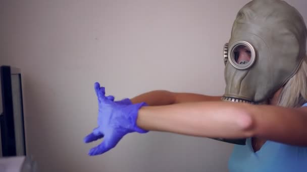 A woman in a gas mask and medical gloves works at home on a computer - Footage, Video