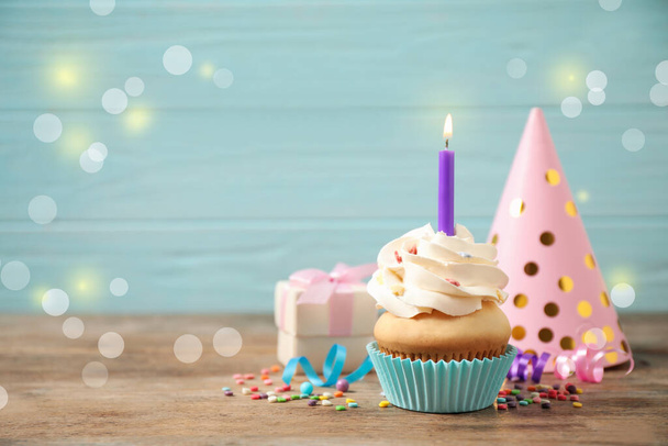 Birthday cupcake with burning candle on wooden table against grey background, space for text. Bokeh effect - Foto, afbeelding