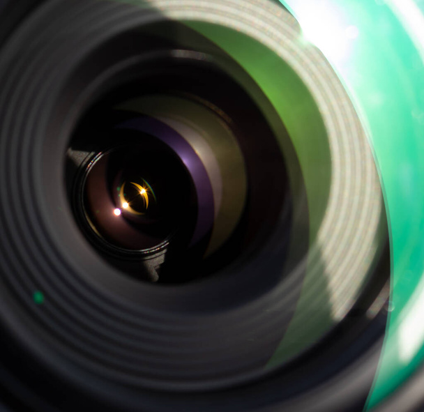 Close up de uma lente de câmera, com elementos de vidro refletindo luz solar brilhante e nítida em muitas cores semelhantes à galáxia
. - Foto, Imagem