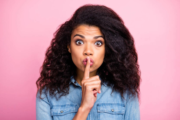 Funny funky afro american girl hear unbelievable information impressed say dont share put index finger mouth lips wear denim jeans shirt isolated over pink color background - 写真・画像