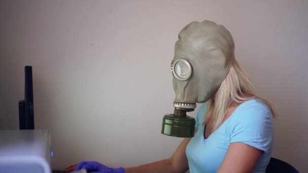 Una mujer con una máscara de gas o respirador trabaja en casa en una computadora. Prevención del Coronovirus
 - Imágenes, Vídeo