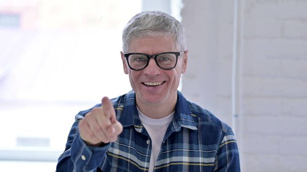 Retrato de un hombre casual de mediana edad señalando con el dedo a la cámara
 - Foto, Imagen