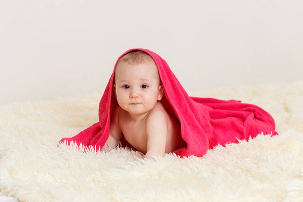 eight-month-old baby under a pink blanket.baby girl after bathing lying on her stomach - Fotoğraf, Görsel