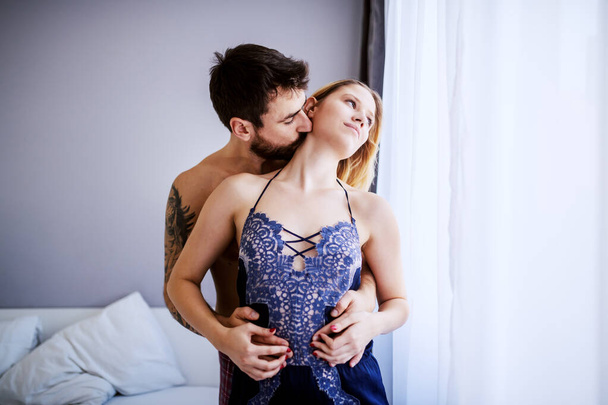 Joven pareja atractiva apasionada abrazándose en el dormitorio. Hombre en besar a su amada novia
. - Foto, Imagen
