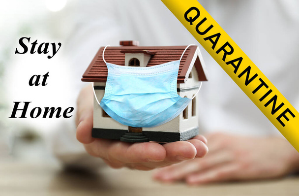 Stay at home during coronavirus quarantine. Man holding house model with medical mask - Foto, Imagen