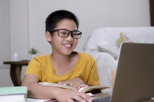 Задоволений використанням комп'ютерних онлайн-навчальних робіт. Азіатський хлопчик отримує задоволення від самостійного навчання вдома. Онлайн-освіта, самовивчення та домашнє навчання. - Фото, зображення