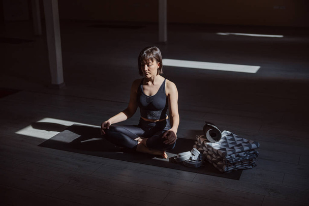 Junge ruhige Yogi-Frau in Lotus-Yoga-Pose. Innenraum Yoga-Studio. - Foto, Bild