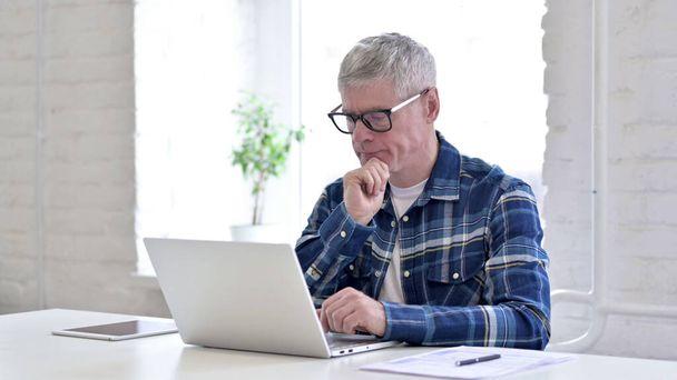 Alkalmi középkorú férfi gondolkodás és dolgozik a laptop - Fotó, kép