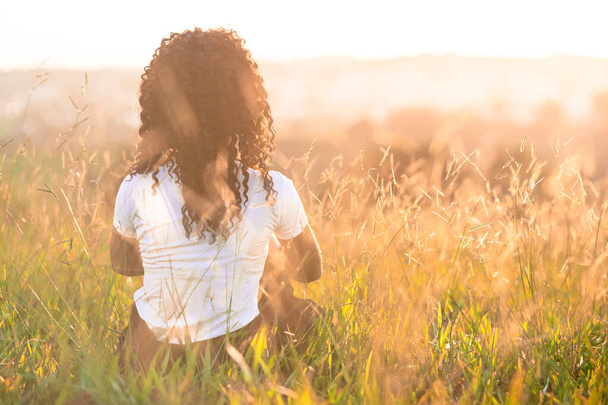 Αφρο-Αμερικάνα με την πλάτη στο χωράφι το ηλιοβασίλεμα. - Φωτογραφία, εικόνα