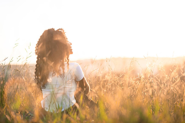 afro amerikai lány a hátán ül a mezőn napsütésben - Fotó, kép