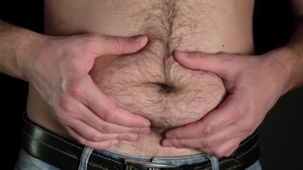 Egy férfi pózol kövér gyomorral a feketén. Közelről.. - Felvétel, videó