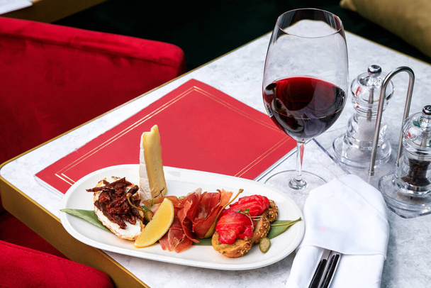 bruschetta with salmon hamon and sun-dried tomatoes and a glass of red wine. Place for text. - Photo, Image
