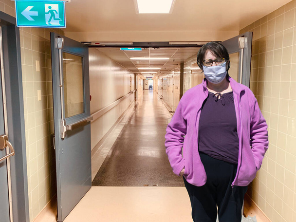 Idős nő védő orvosi maszkban, elszigetelve az üres kórházi folyosótól. Coronavirus idős tanács. Biztonsági öregek. Vírusátvitel érintéssel. Fénymásolási hely. - Fotó, kép