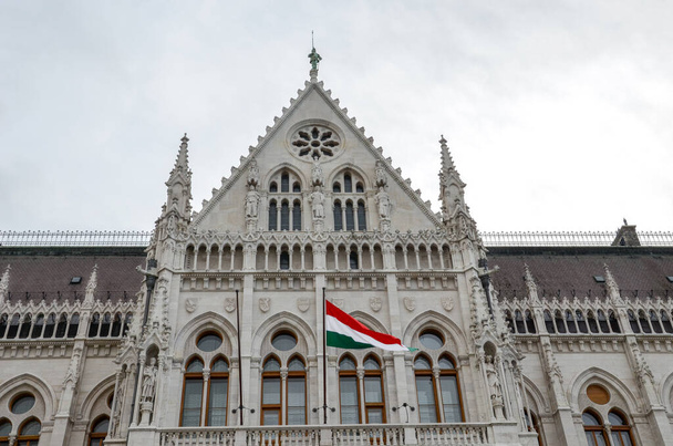 Здание венгерского парламента Оршагхаз в Будапеште, Венгрия. Место Национального Собрания. Дом построен в неоготическом стиле. Размахивание флагом Венгрии на дому. Венгерская концепция
. - Фото, изображение