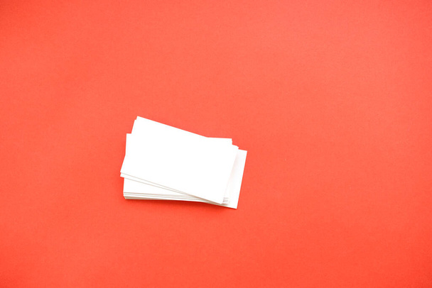 una pila de tarjetas de visita vacías sobre un fondo rojo. muchas tarjetas de visita
 - Foto, Imagen