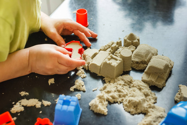 Carino età bambino di 3 anni gioca sabbia cinetica a casa. Occupazione con un bambino in quarantena
. - Foto, immagini