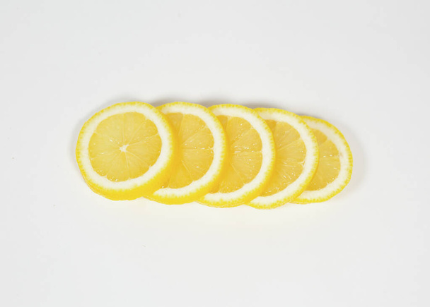 Slices of ripe juicy lemon full of vitamins lie horizontally on top of each other on a white isolated background - Foto, immagini
