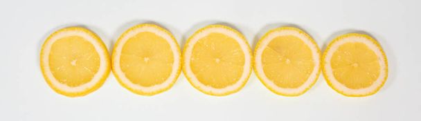 Slices of ripe juicy lemon full of vitamins lie horizontally on a white isolated background - Foto, afbeelding