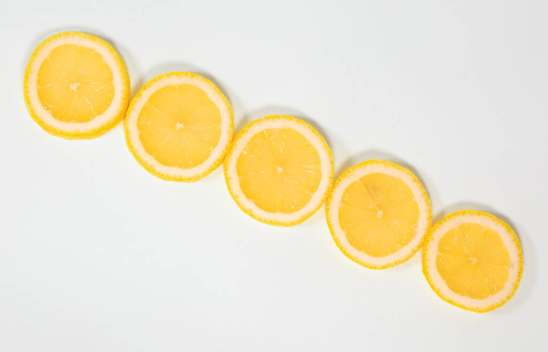 Slices of ripe juicy lemon lie diagonally on a white isolated background - Photo, Image