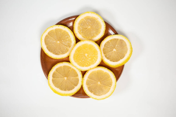 Slices of ripe juicy lemon full of vitamins lie on a clay saucer in the shape of a star, lemon on a white isolated background - Foto, Bild
