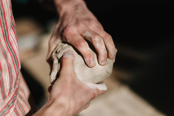 Il primo piano dell'uomo lavora con l'argilla. Maschio ceramista impasta e inumidisce l'argilla prima del lavoro, tonica
 - Foto, immagini