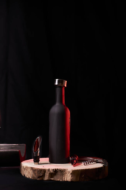 Μπουκάλι και σκεύη κρασιού σε ξύλινο κούτσουρο, σε μαύρο φόντο - Φωτογραφία, εικόνα