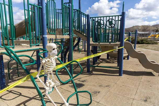 Дорослий скелет сидить на ігровому обладнанні в порожньому закритому парку в гарний день
 - Фото, зображення