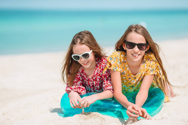 Pieni onnellinen hauskoja tyttöjä on hauskaa trooppisella rannalla leikkii yhdessä. - Valokuva, kuva