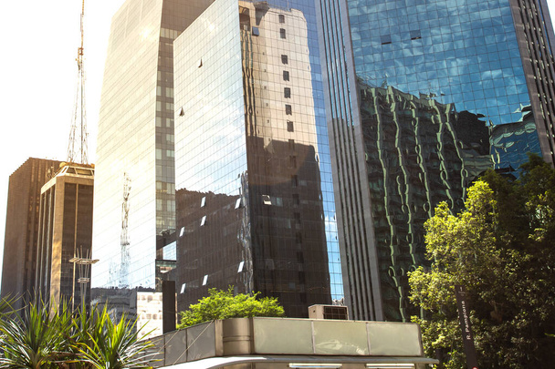 Vállalati épületek az Avenida Paulista-n, üvegburkolatukkal, ami gyönyörűen tükrözi a többi épületet, fákkal körülvéve.. - Fotó, kép