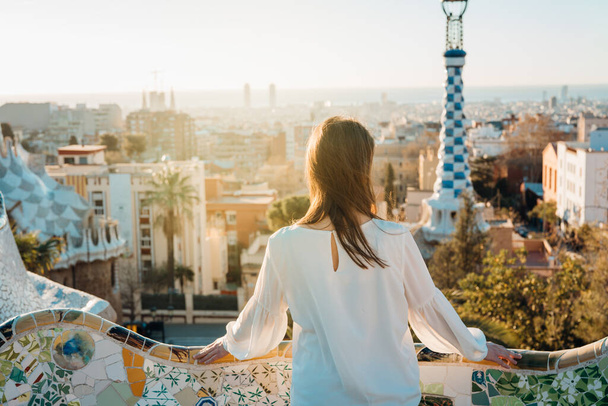 Young female tourist spending vacation in Barcelona,Catalonia,Spain.Traveling to Europe,visiting Parc Guell UNESCO site famous historical landmarks.Panoramic view on entrance.Best sunrise in Barcelona - Foto, Bild