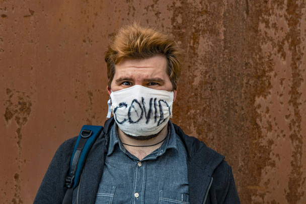 férfi maszk önvédelmi akció globális karantén corona vírus körülmények között idő, depresszió férfi portré rozsdás fal háttér - Fotó, kép