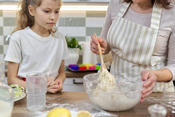 Mother and daughter at kitchen kneading dough in bowl, close-up - Foto, imagen
