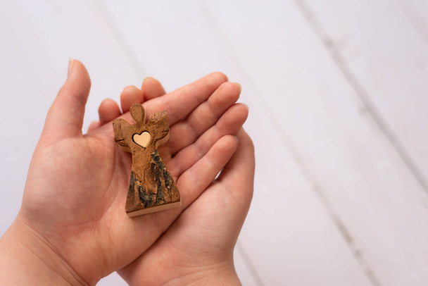 дерев'яний ангел тримається в дитячих руках з білим тлом
 - Фото, зображення