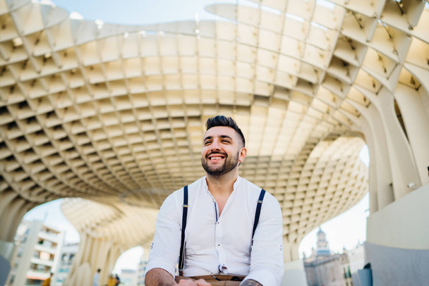 Attractive smiling young man influencer.Tourist visiting Setas de Seville,Metropol Parasol, site seeing attractions.Vacation in south of Spain, blogger lifestyle.European Andalucia road trip - Foto, afbeelding