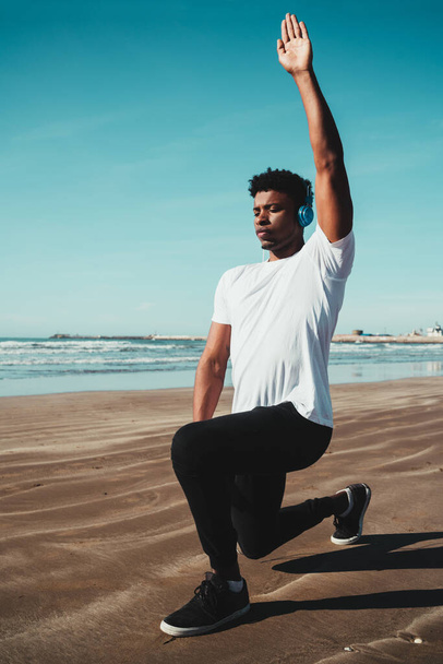 Portrait of an athletic man doing exercise at the beach. Sport and healthy lifestyle concept. - Fotó, kép