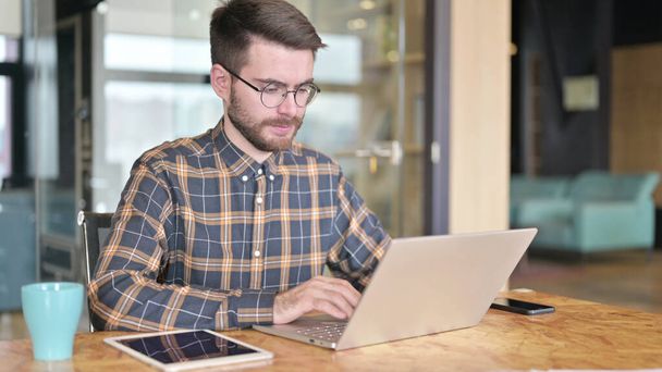 Молодий дизайнер використовує ноутбук в сучасному офісі
 - Фото, зображення