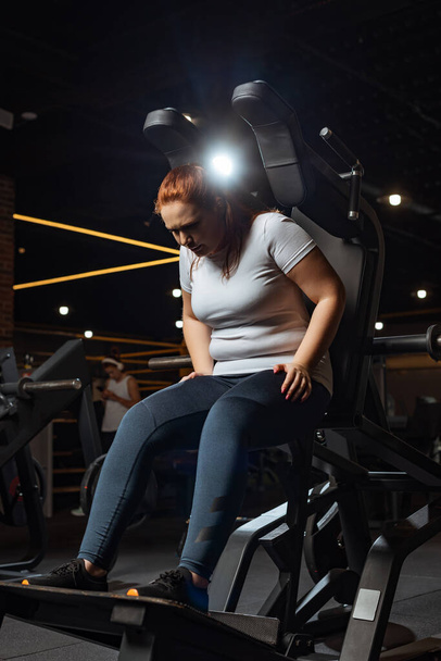 overweight girl in sportswear training on fitness machine in gym - Photo, Image