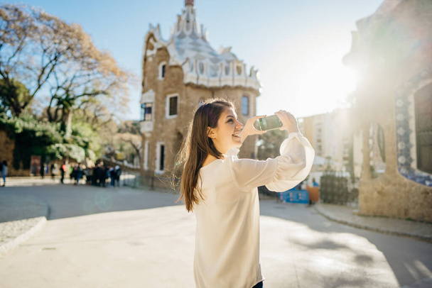 Happy tourist mking pictures with smartphone at landmark.Traveling to Spain,visiting famous Parc Guell, Barcelona.Tourist using smartphone app for sightseeing tour.Travel photography for social media - 写真・画像