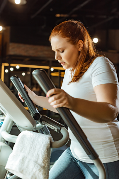 focused overweight girl training on step machine in gym - Foto, Bild