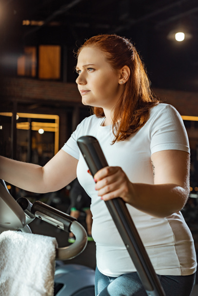 confident overweight girl training on stepper in sports center - Photo, Image