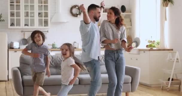 Carefree parents and cute children dancing having fun in kitchen - Imágenes, Vídeo