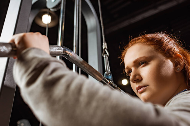 valikoiva painopiste luottavainen ylipainoinen tyttö tekee aseiden laajennus liikunta kunto kone
 - Valokuva, kuva