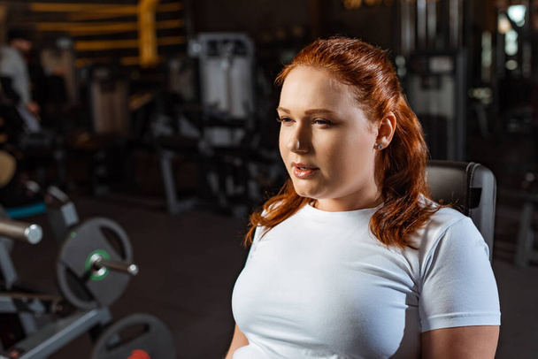 confident, pretty overweight girl in white t-shirt training in gym - Фото, зображення
