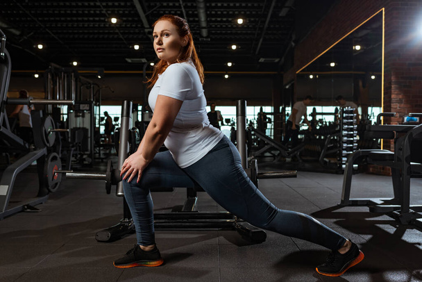 pretty, overweight girl doing lounges exercise in gym - Photo, Image