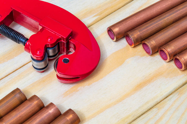 Красные трубы и медные трубы с разъемами для ремонта сантехники на деревянных досках
 - Фото, изображение