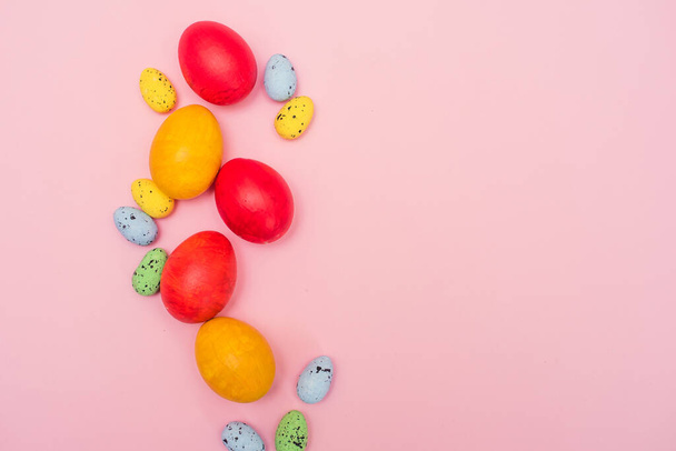 Huevos de color Pascua sobre un fondo rosa. Huevos de pollo rojo y amarillo con huevos de codorniz pastel. Tarjeta de Pascua. Copiar espacio. - Foto, imagen
